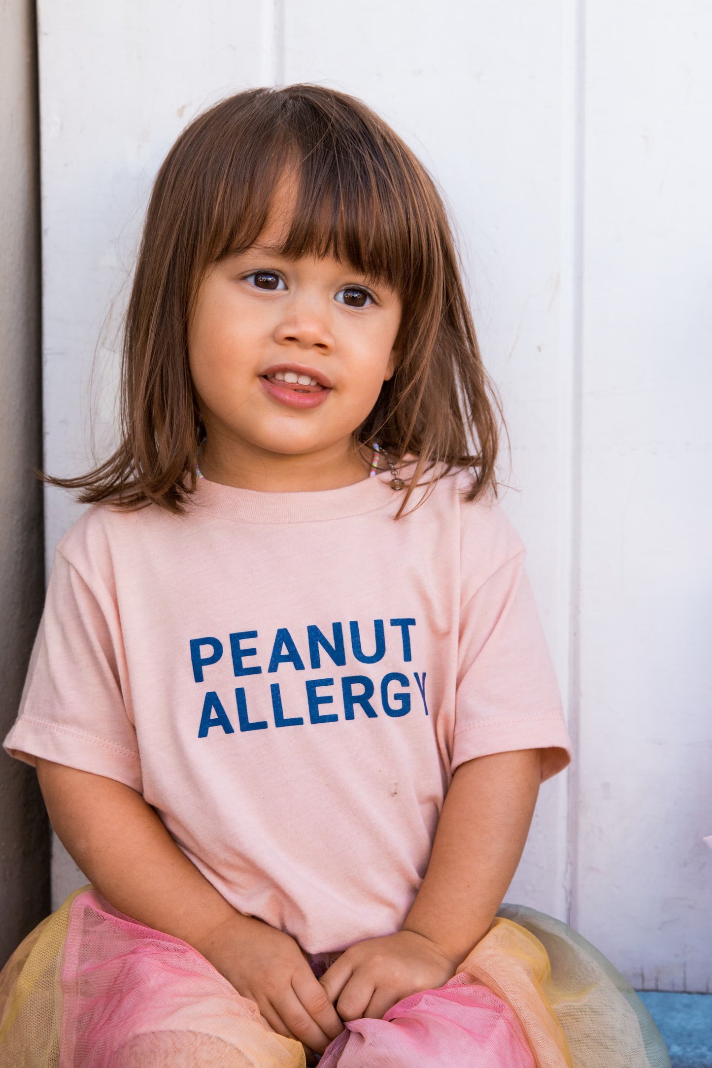 girl in peach peanut allergy shirt with peanut allergy text